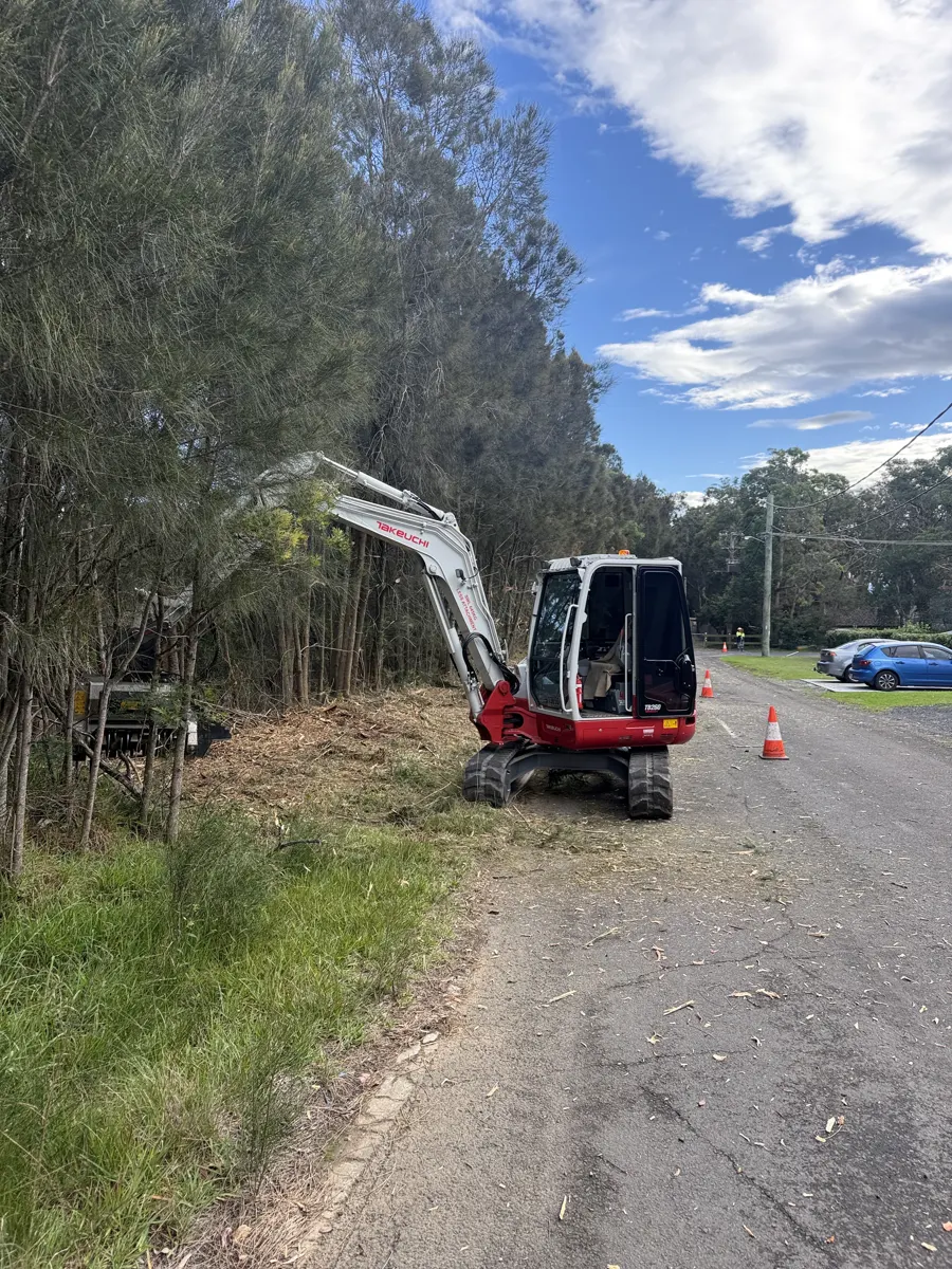 Excavator clearing roadside vegetation for a council job